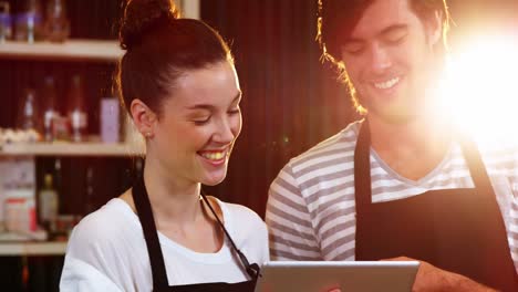 Waiter-and-waitress-discussing-over-digital-tablet