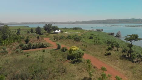 aerial shot tracking a car on a dusty dirt road by the shores of lake victoria in rural africa