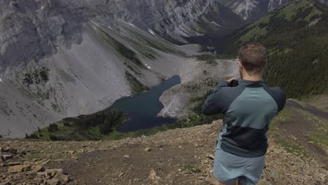 Hiker-on-mountain-ridge-taking-photos-Rockies-Kananaskis-Alberta-Canada