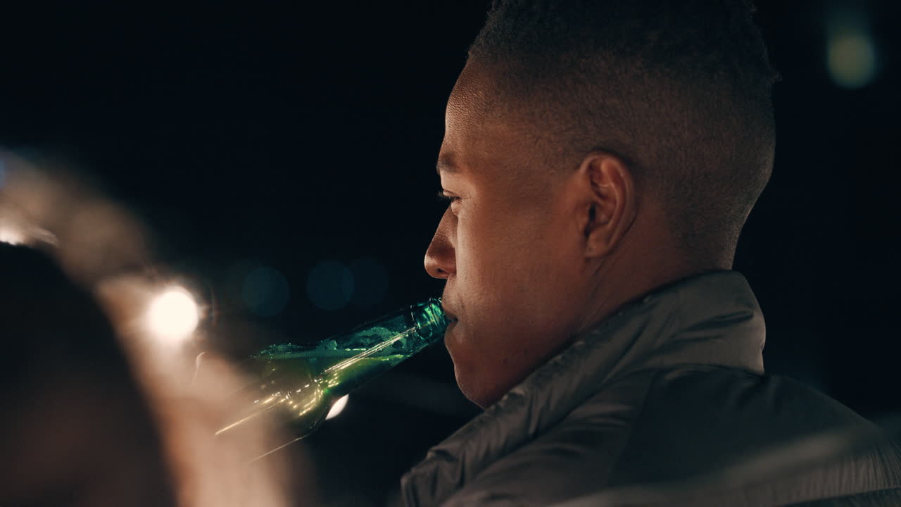happy african american man drinking alcohol enjoying rooftop party celebration hanging out with friends on weekend of at night