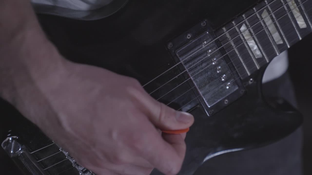 hombre recogiendo rápidamente cuerdas de guitarra eléctrica mientras practica