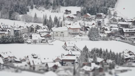 a snow-covered tyrolean village with alpine houses and hotels at the foot of the skiing slope nestled in the dolomites.