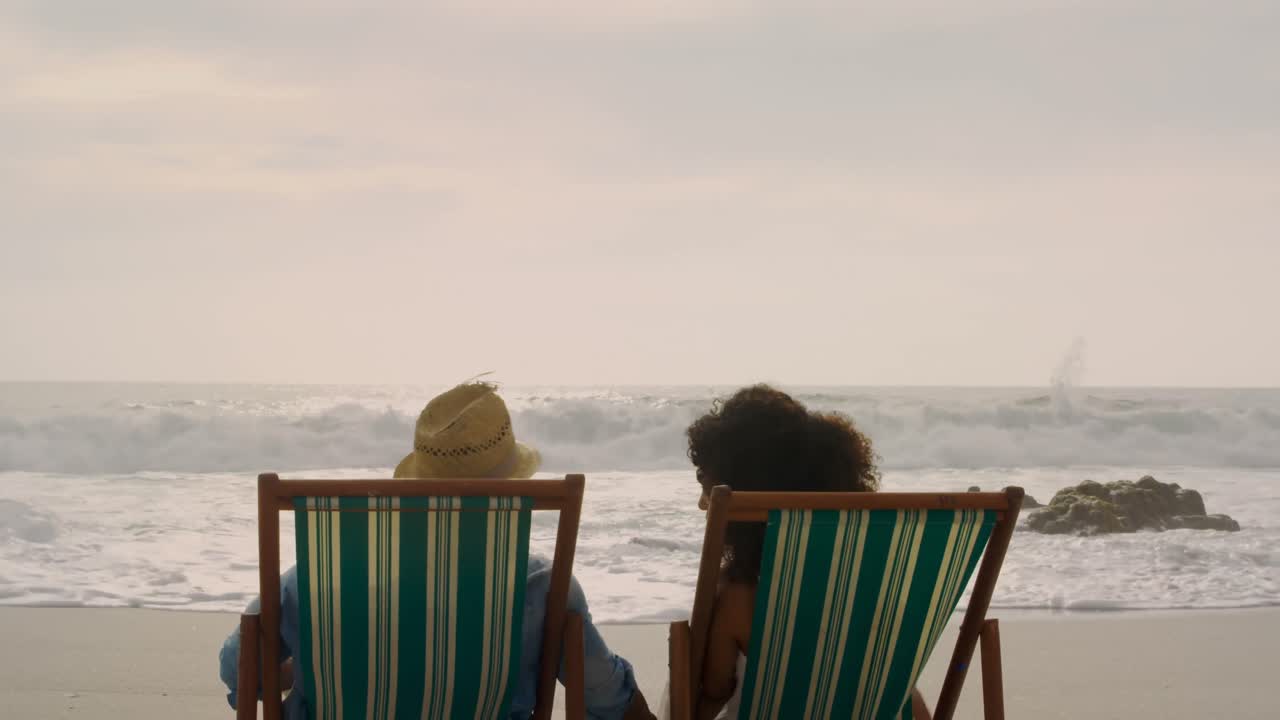 아프리카계 미국인 부부 가 해변 4k 의  ⁇ 자리 에서 함께 휴식을 취하고 있는 뒤쪽 전망