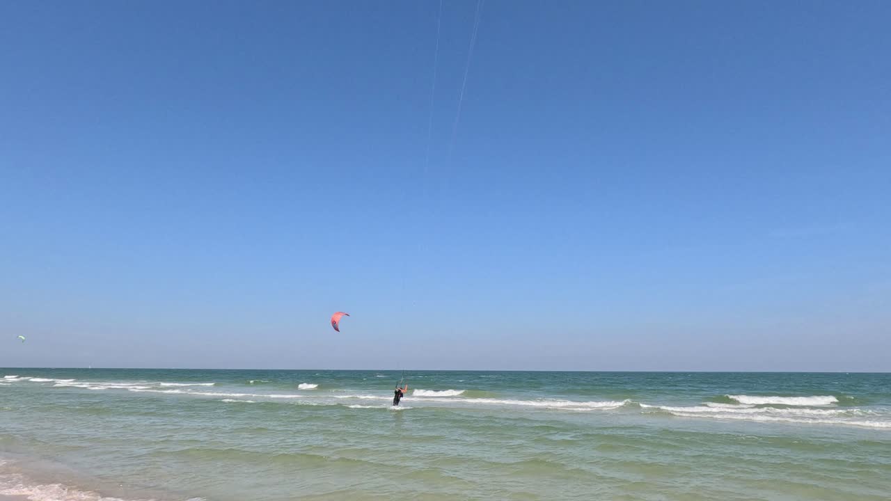 kite surfer deslizándose sobre el mar con una cometa roja