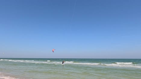 kite surfer gliding over the sea with a red kite