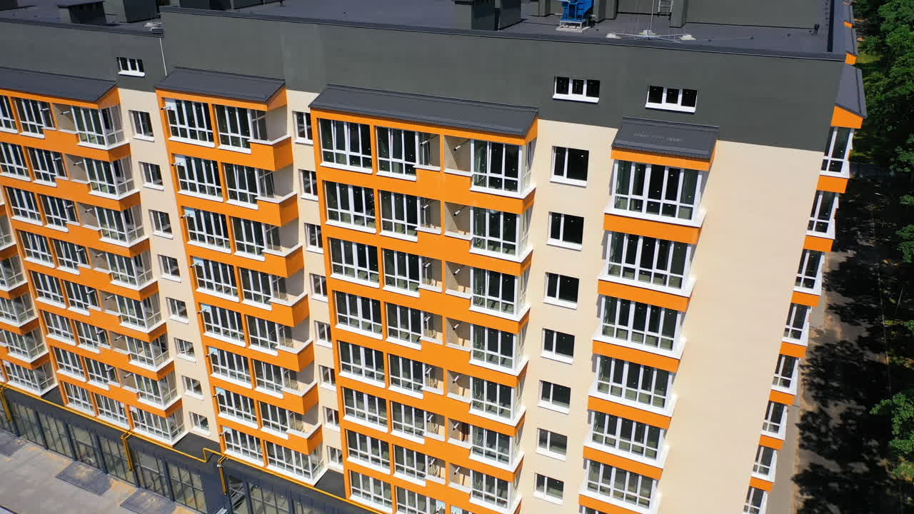 New high-rise building of modern design. Multi storey building with large covered balconies in orange color. Motion camera down.