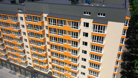 new high-rise building of modern design. multi storey building with large covered balconies in orange color. motion camera down.