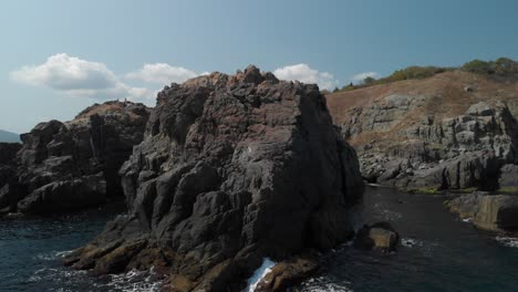 aerial tracking shot of big rocks on the seashore in sunny summer day