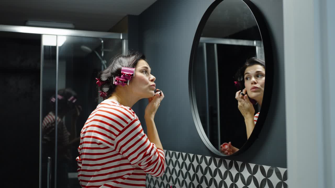 mujer adulta aplicando rubor haciendo maquillaje en el baño