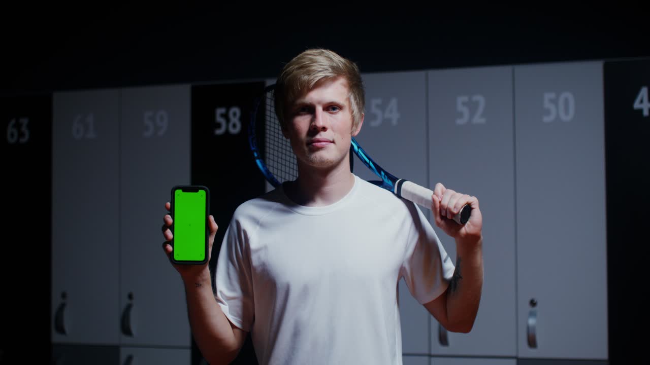 옷차림실 에서 테니스 라켓 과 전화 를 들고 있는 사람