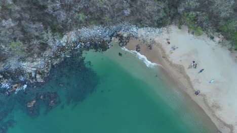 Overhead-vistas-of-Playa-Maguey,-displaying-its-lush-emerald-green-shades-against-backdrop-of-Huatulco,-Oaxaca