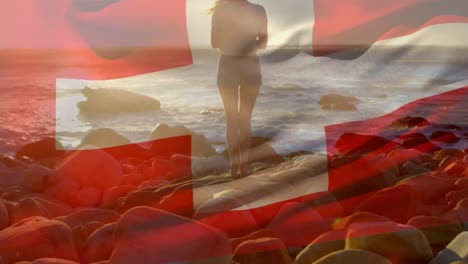 animation of flag of switzerland over caucasian woman at beach