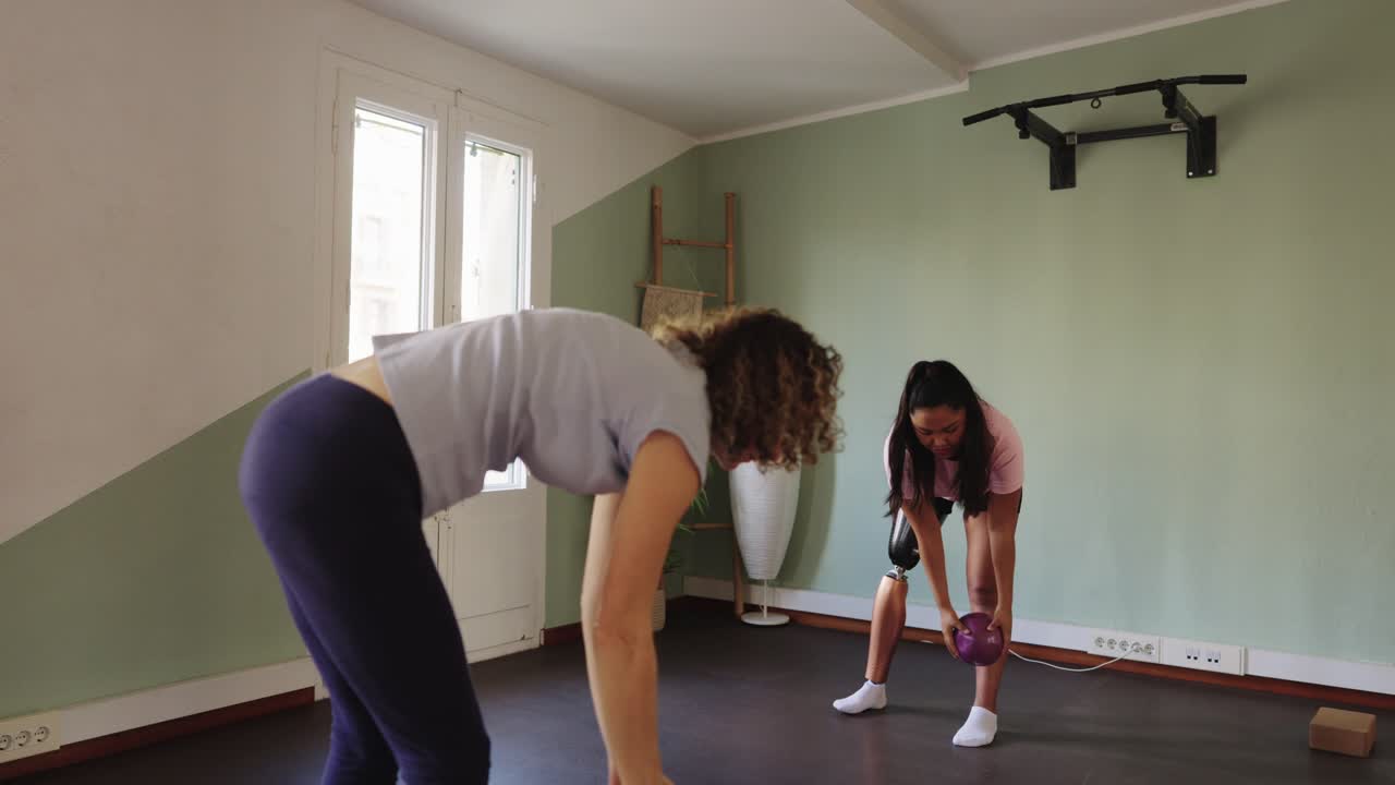 Dos mujeres haciendo ejercicio con balones medicinales en un gimnasio en casa
