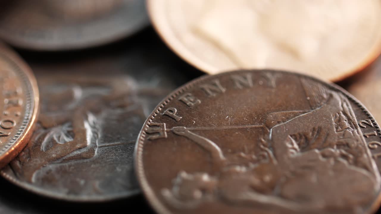 Stacked British one penny coins with visible patina and classic Britannia design, close-up rotating macro view