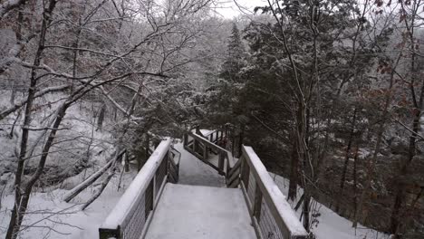 Pov-Wandern-Auf-Verschneiter-Fußgängerbrücke-Im-Wald-Zu-Einer-Aussichtsplattform,-Winterszene