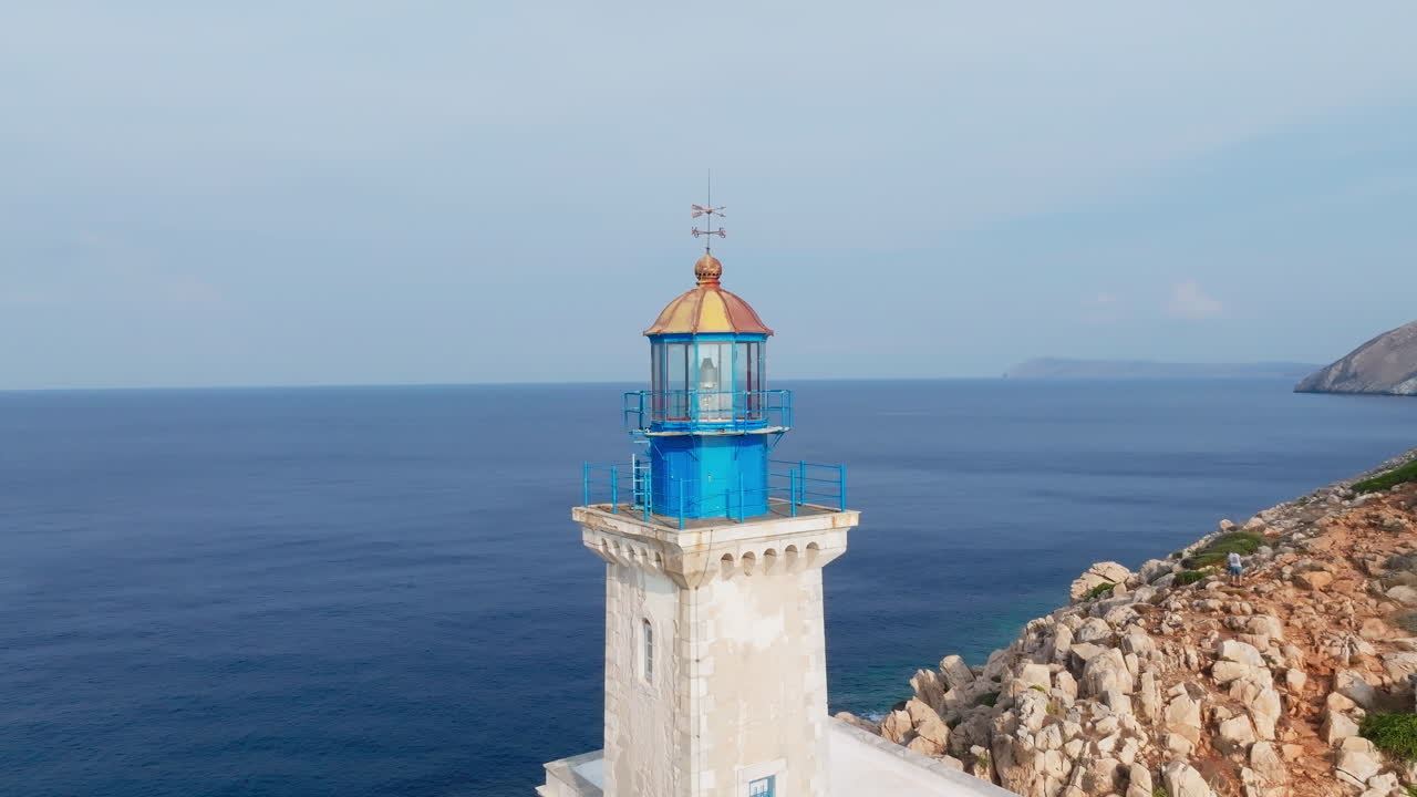 Cape Tainaron Lighthouse stands atop rocky hill overlooking sea, from drone at distance