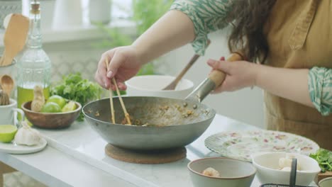 woman serving tasty wok pasta on plate