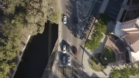 4K-cinematic-overhead-shot-of-Los-Angeles-river-and-surrounding-suburban-streets-with-sunlit-birds-flying-through-frame