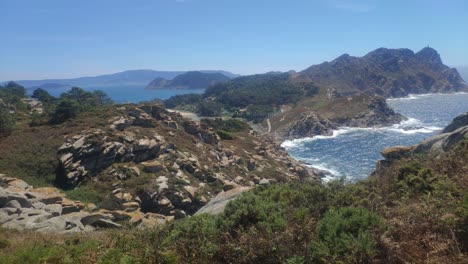 isla montañosa con acantilados y playas con niebla de calor, día soleado, toma panorámica girando lentamente a la derecha, islas cíes, pontevedra, galicia, españa