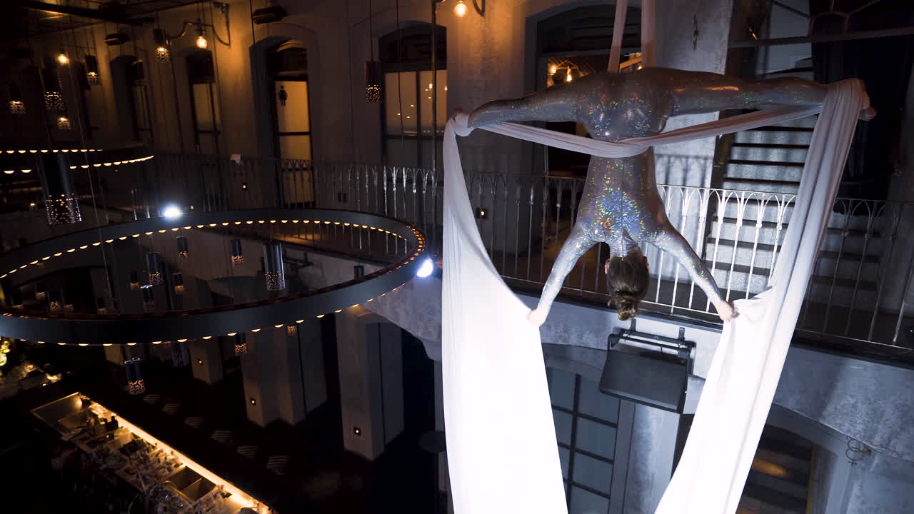 음악 클럽에서 거꾸로 스트래들 포즈를 취하는 여성 공중 곡예사