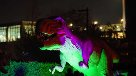 T-rex-robot-dinosaur-moving-in-children-theme-park-illuminated-at-night