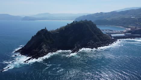 Deep-blue-water-of-Biscay-Bay-in-sunshine,-Getaria-lighthouse-on-coast