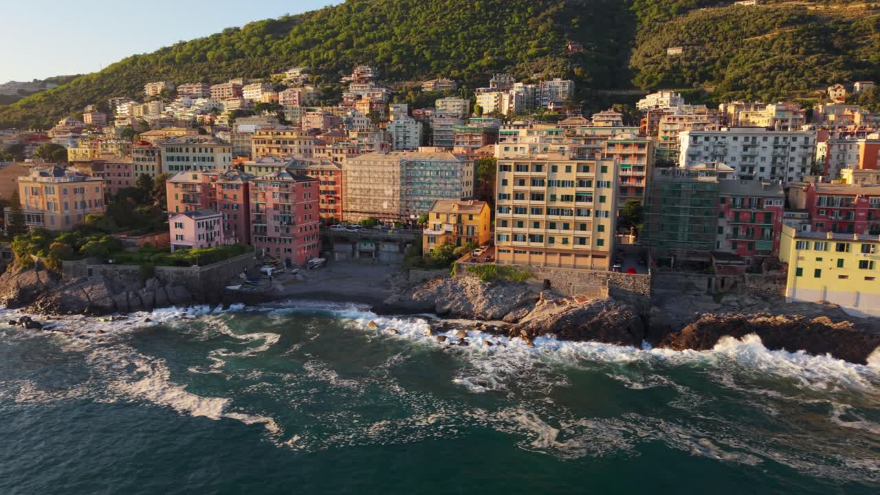 Coastal view of colorful buildings by the Mediterranean Sea at sunset with waves