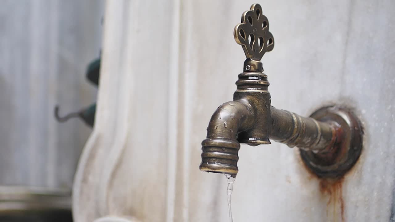 Primo piano di un rubinetto in ottone vintage che gocciola acqua