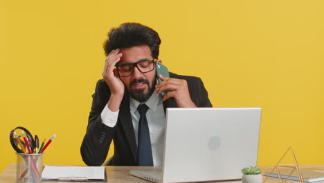 tired sleepy indian business man having annoyed boring talk conversation on smartphone with client