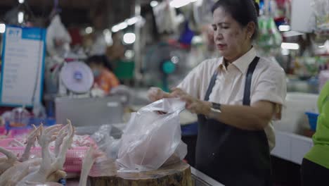 woman packing fresh chicken at asian market