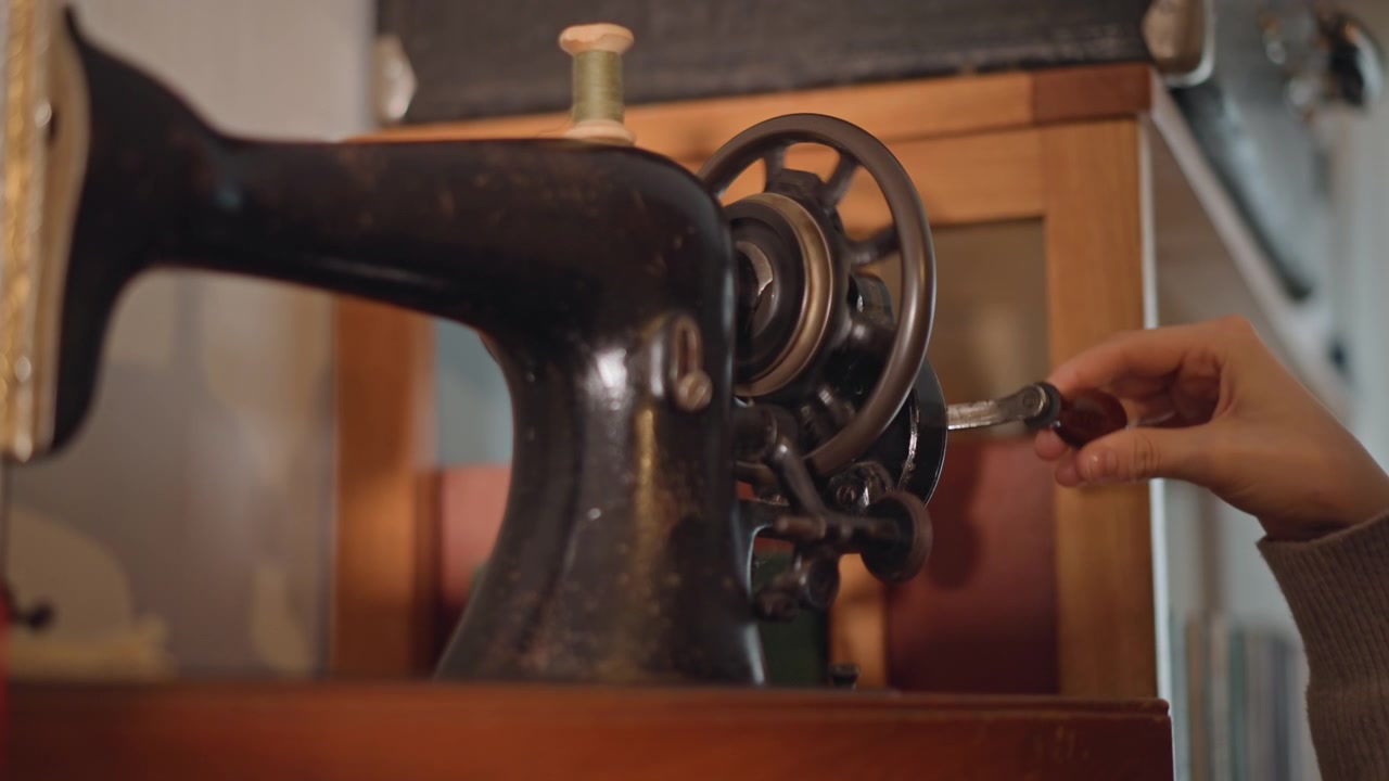 Vintage maskine tester håndværk. Kvinde engagerer sig aktivt i retro symaskinedemonstration. Kvinde betjener passioneret gammeldags symaskine i varmt oplyst studiemiljø