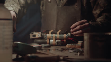 a bombmaker assembles a bomb in his workshop at night