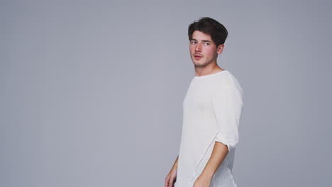 studio shot of man walking into frame against white background and dancing in slow motion