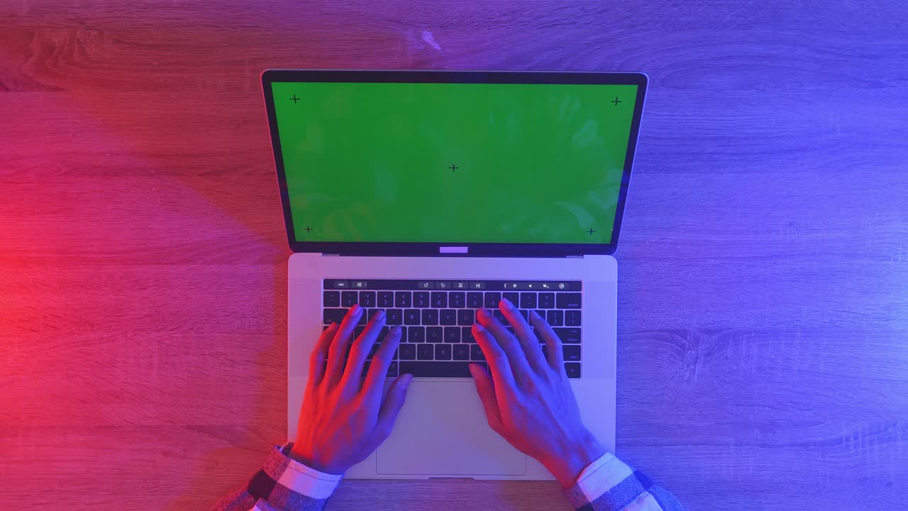 vista de cima para baixo de um computador portátil com maquete de tela verde chromakey exibição em uma mesa de escritório de madeira ao lado do caderno com canetas, copos e um copo de água. zoom lento para fora, fechar