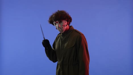 man in white mask with big sharp knife on blue background with red neon light image of jason