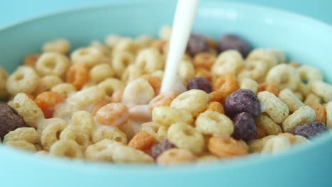 pouring milk on cereal in a blue bowl