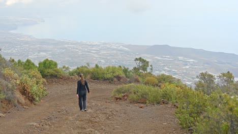 Slowmo,-tourist-hiking-down-steep-trail,-looking-over-scenic-Guimar-Valley