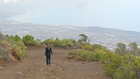 slowmo, turista caminando por un sendero empinado, mirando el pintoresco valle de guimar