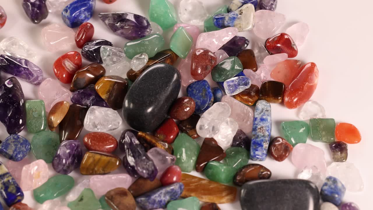 Vibrant gemstones spill from a purple velvet pouch onto a white surface, showcasing a variety of colors and textures