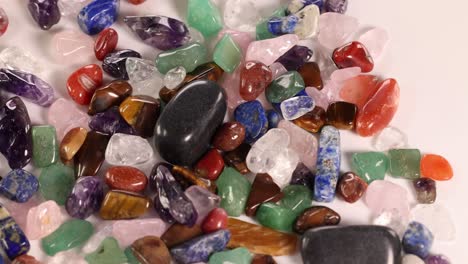 vibrant gemstones spill from a purple velvet pouch onto a white surface, showcasing a variety of colors and textures