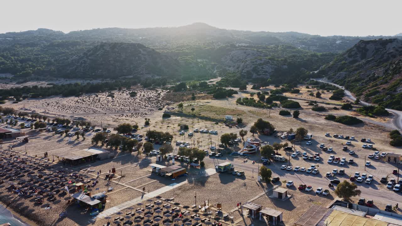 Aerial view of a beach with parking lot and mountain backdrop