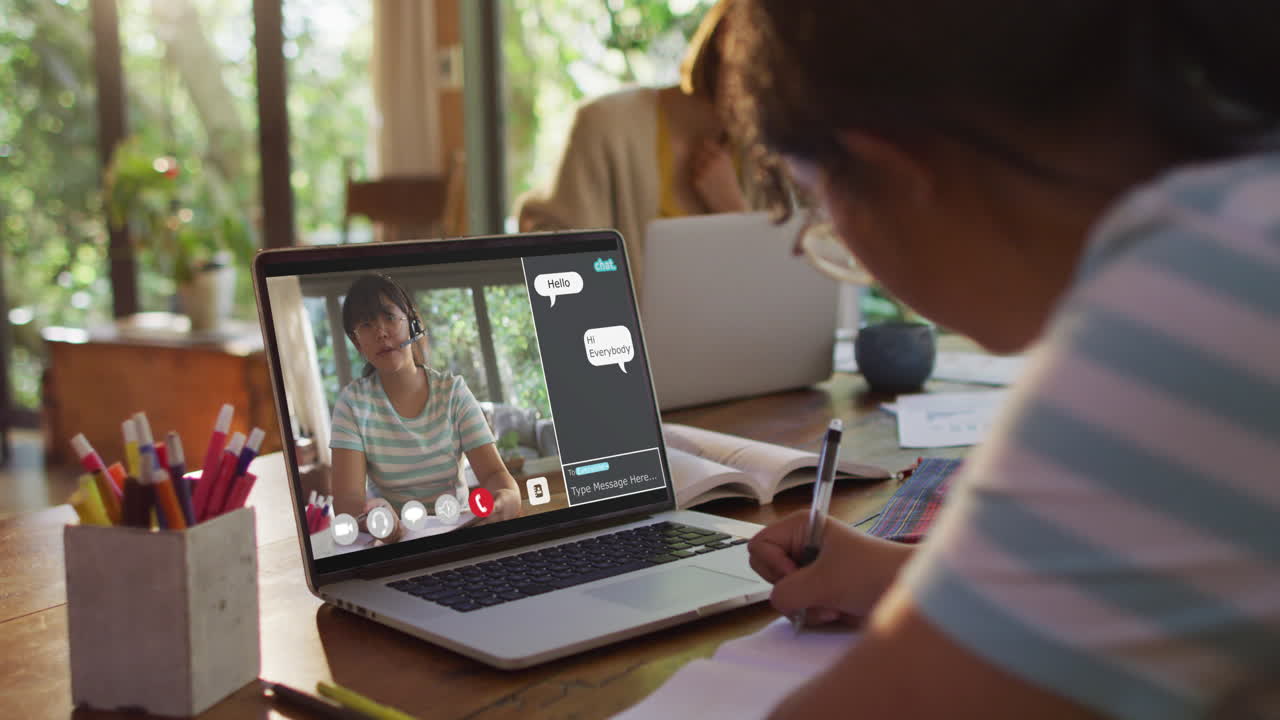 African american girl doing homework and having a video call with female teacher on laptop at home