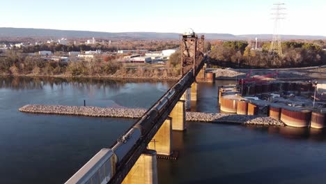 Aerial-view-slow-motion-shot-of-Chickamauga-Dam,-Rail-passing-on-the-Bridge,-Chattanooga-TN-river-water-flowing-below-on-a-sunny-day-in-USA