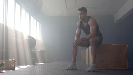 resting on wooden box, man in gym taking break from workout, copy space