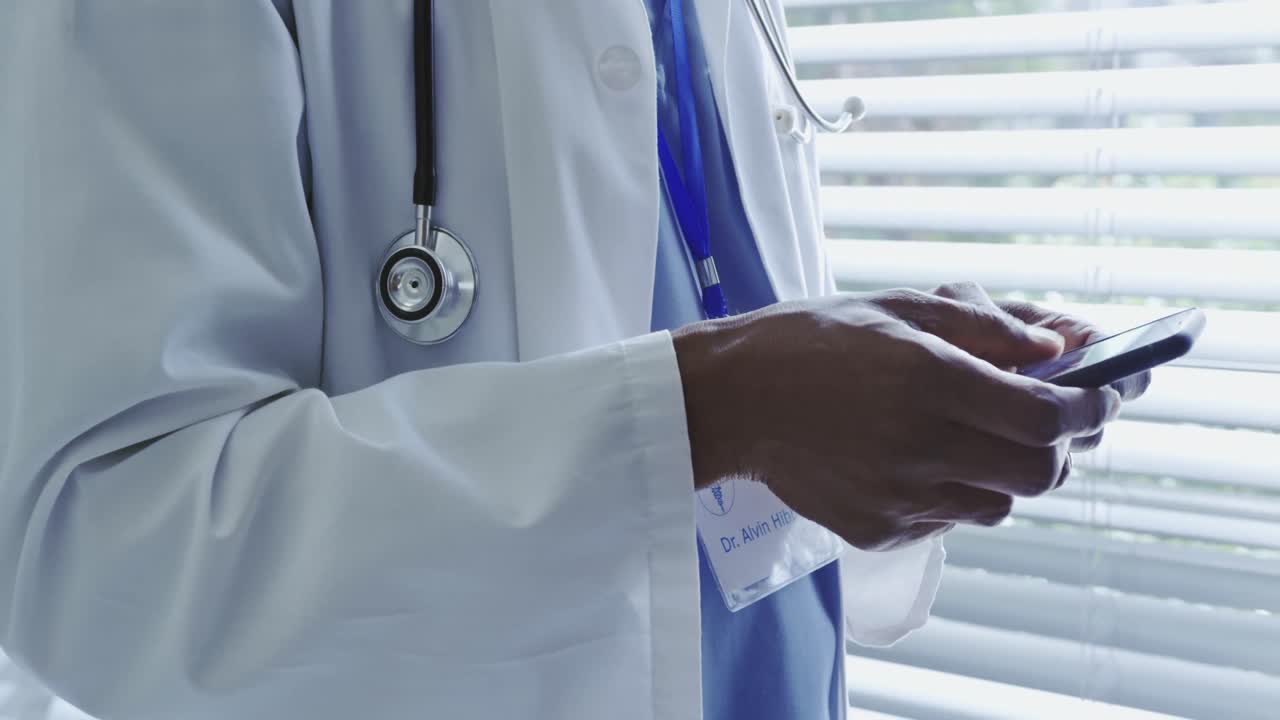 Mid section of African American male doctor using mobile phone in hospital 4k