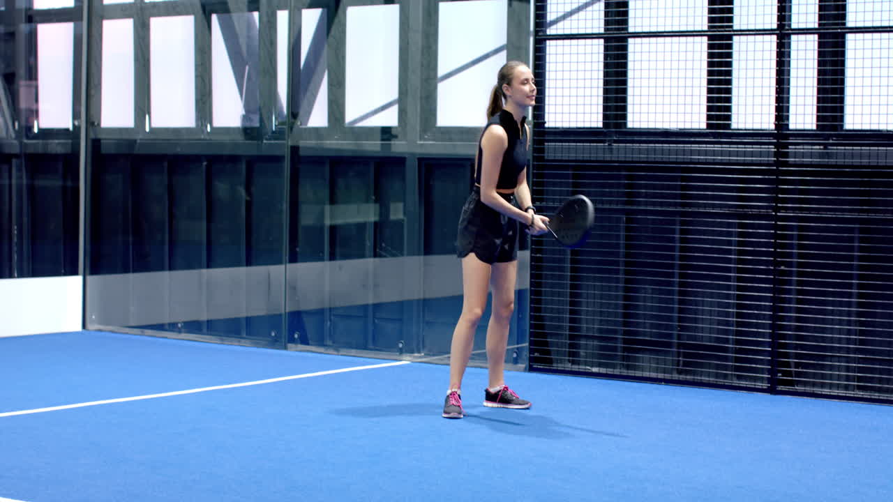 Young man playing padel tennis, preparing to serve on indoor court