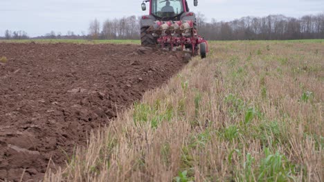 Low-POV-handheld-shot-of-farm-tractor-plowing-land