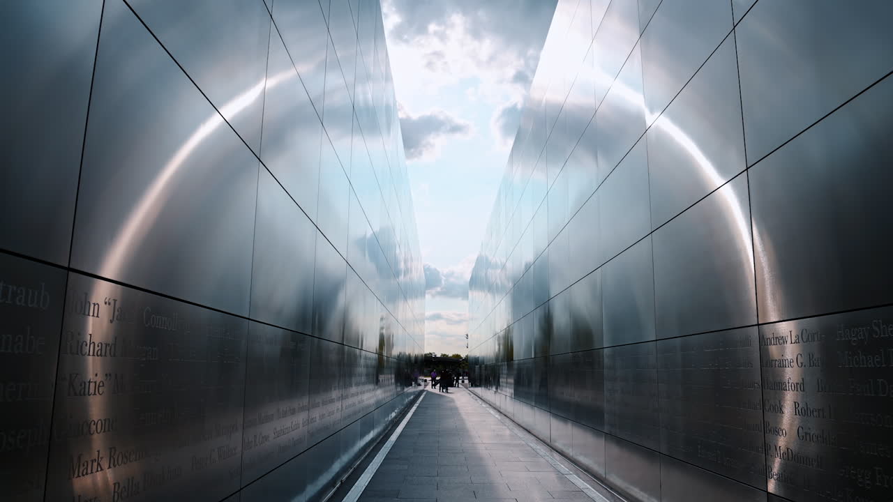 Jersey City, USA, 1 July 2025: Walking along the metal walls with multiple engraved names. People stand at the end of the Empty Sky memorial in New Jersey, USA