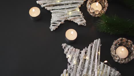 Video-of-christmas-decorations-with-candles,-stars-and-copy-space-on-black-background