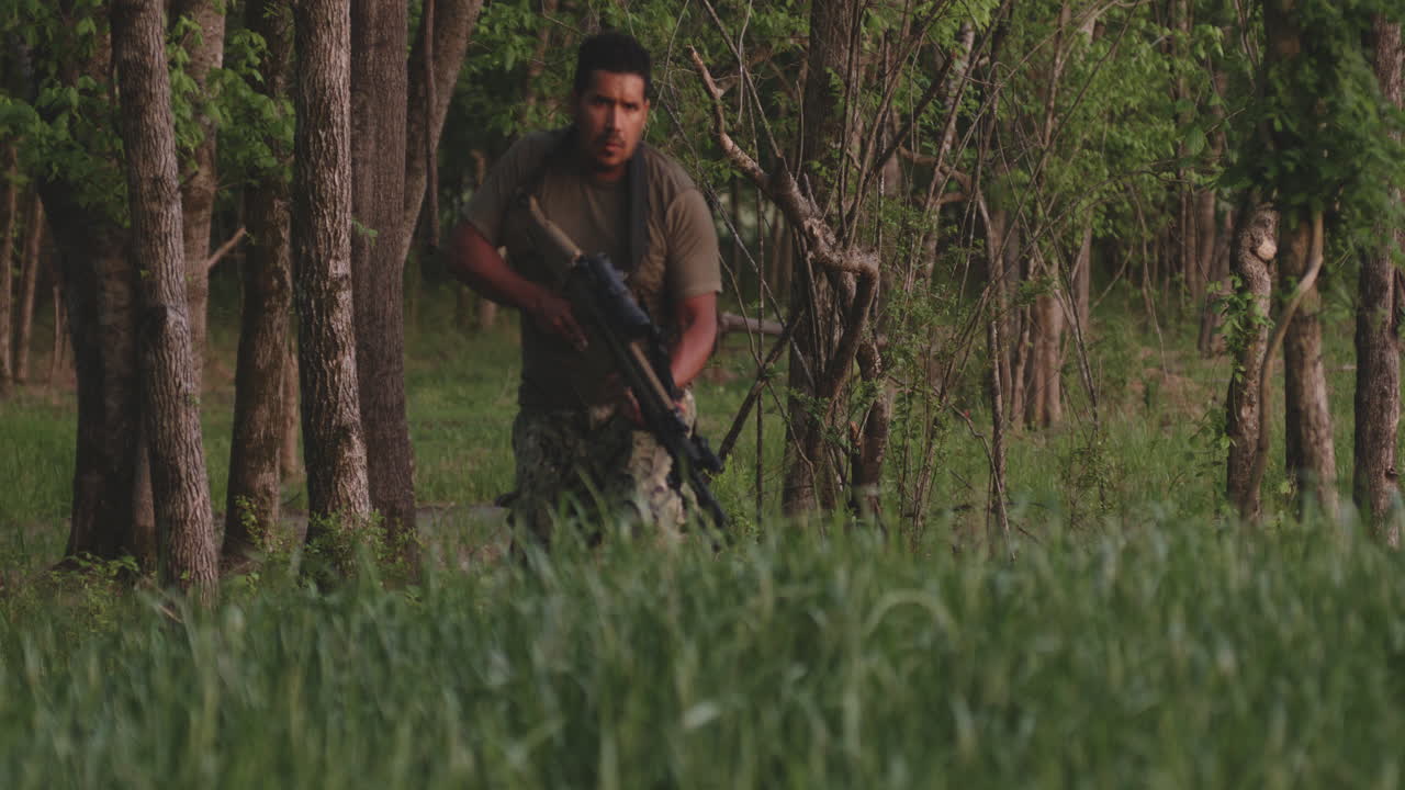 A man with a rifle moving cautiously through a forest in Collierville, Tennessee, USA